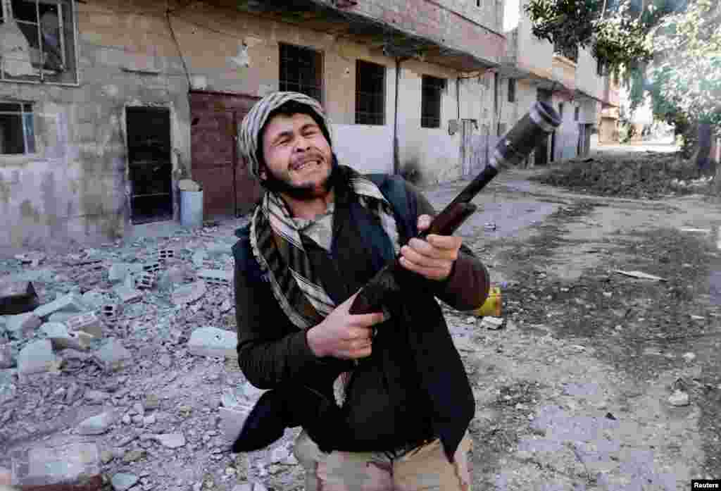 A fighter from the Free Syrian Army uses a shotgun to fire a grenade at Syrian Army soldiers in the Arabeen neigborhood of Damascus, February 9, 2013. 