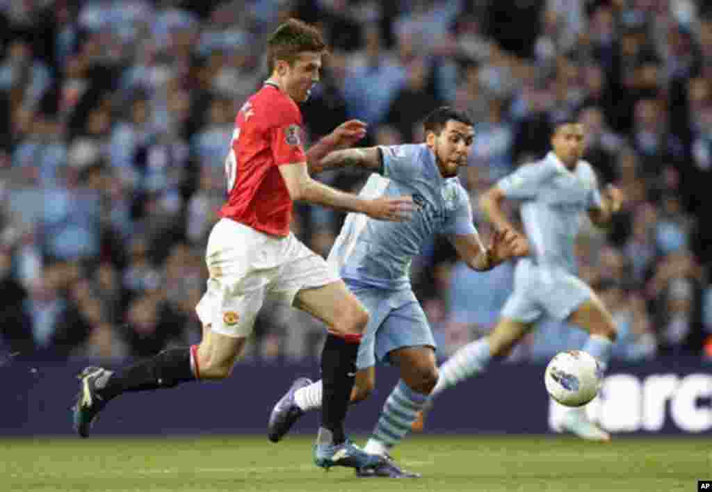 Manchester City's Carlos Tevez, centre, fights for the ball against Manchester United's Michael Carrick during their English Premier League soccer match at The Etihad Stadium, Manchester, England, Monday, April 30, 2012. (AP Photo/Jon Super)