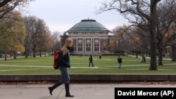 FILE - In this Nov. 20, 2015 file photo, University of Illinois students walk across the campus in Urbana, Illinois. The school has identified at least 14 cases of misleading financial aid applications. (AP Photo/David Mercer, File)