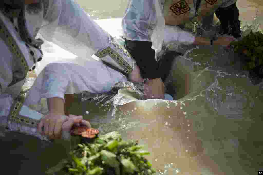 Christian Orthodox priests re-enact the baptism of Jesus, during the traditional Epiphany baptism ceremony at the Qasr-el Yahud baptism site in the Jordan river near the West Bank town of Jericho.