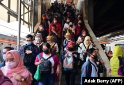 Para komuter yang mengenakan masker wajah berjalan ke peron kereta mereka di stasiun kereta Tanah Abang di Jakarta pada 18 Agustus 2020. (Foto: AFP/Adek Berry)