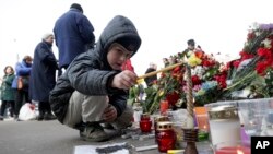 一个小男孩在俄罗斯圣彼得堡先纳亚广场地铁站前的一个象征性悼念地点点燃蜡烛（2017年4月4日）