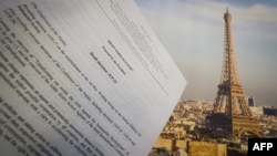 An illustration picture taken on Dec. 10, 2015 in Paris shows a draft for the outcome of the COP21 United Nations conference on climate change next to a picture of the Eiffel Tower. 