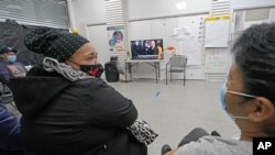 Immigrant worker Blanca Cedillos, center, who is a nanny, glances over at cleaning lady Graciela Uraga, as they watch the presidential inauguration from the Workers Justice Center, a center that supports immigrant workers rights, Wednesday, Jan. 20, 2021