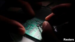 圖為清華紫光的研究人員2016年2月29日在北京的研究中心顯示公司研製的半導體芯片。 