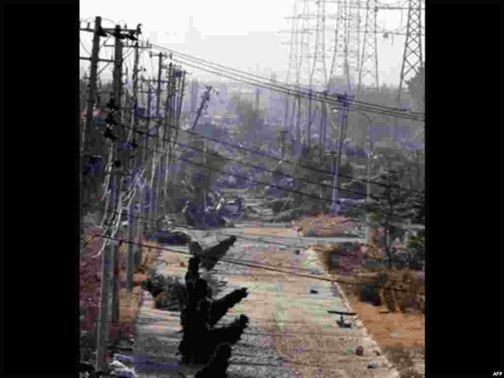 Electric poles stand tilted near a port in Sendai in Miyagi Prefecture (state) one day after a massive Tsunami triggered by a huge earthquake hit northern Japan Saturday, March 12, 2011.