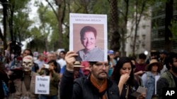FILE - A man holds up a photo of Mexican journalist Miroslava Breach, gunned down in the northern state of Chihuahua on March 23, 2017, during a march in Mexico City, March 25, 2017. 