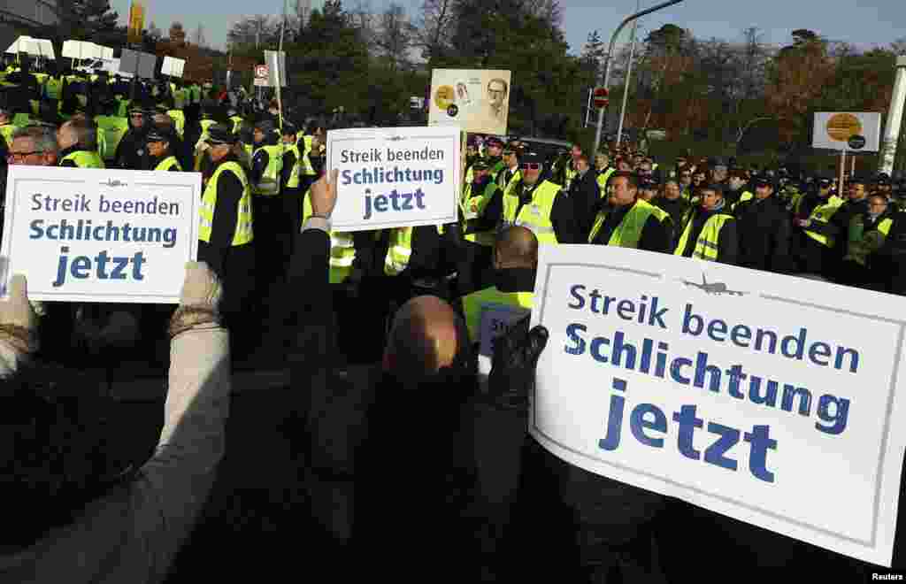 تظاهرات کارگران و خلبانان شرکت هواپیمایی لوفت هانزا در فرودگاه فرانکفورت. پلاکارد&zwnj;های که در دست کارگران است نوشته: &laquo;اعتصاب را پایان دهید &ndash; میانجی گری بکنید.&raquo;