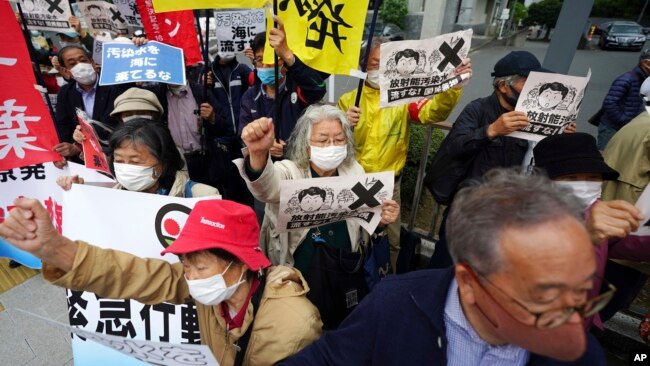 People chant slogans against government's decision to start releasing massive amounts of treated radioactive water from the wrecked Fukushima nuclear plant into the sea, during a rally outside the prime minister's office in Tokyo Tuesday, April 13, 2021.