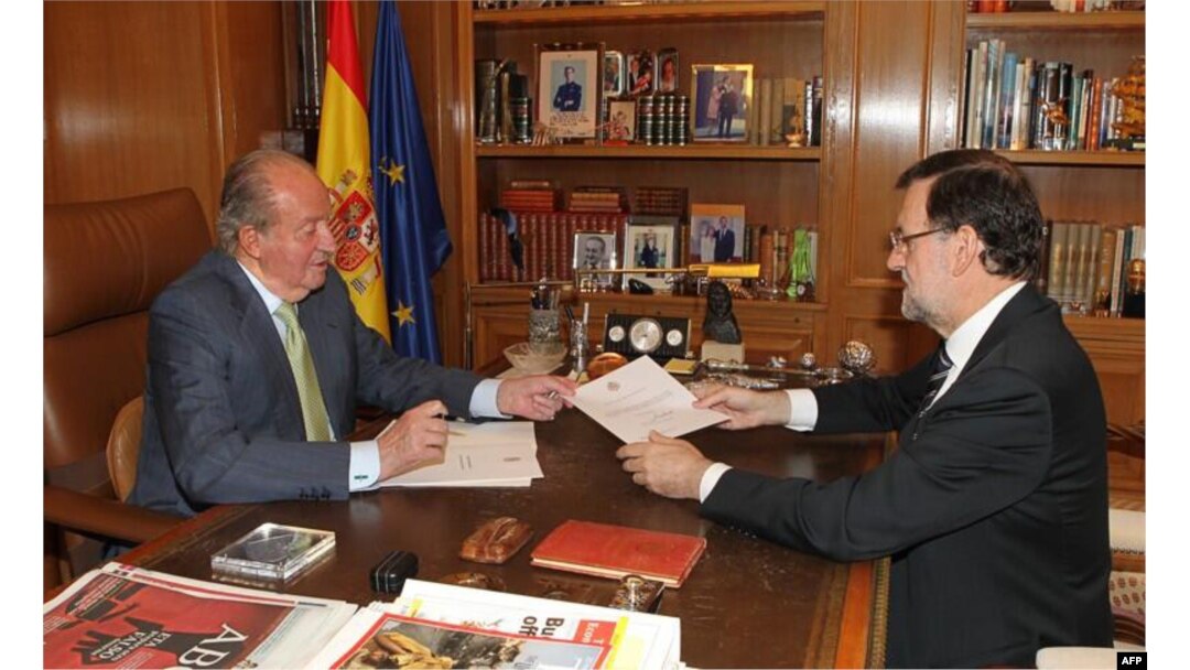 Spain's King Juan Carlos (L) hands over a letter of abdication to Spain's Prime Minister Mariano Rajoy at the Zarzuela Palace in Madrid.