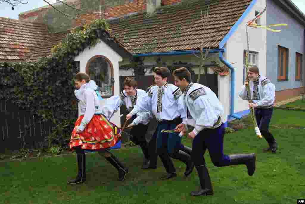 Boys in traditional dresses symbolically beat a girl (L) with small whips during a traditional Easter festivity on Easter Monday in the village of Vlcnov in the southeastern region of the Czech Republic. The whipping of girls on Easter Monday is a tradition that is not intended to cause suffering and a part of the UNESCO Cultural Heritage named Ride of the Kings.
