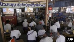 FILE - Customers at a coffee shop in Yangon watch a live television broadcast of new Myanmar President Htin Kyaw delivering his first address at the parliament in Naypyidaw during his swearing in ceremony, March 30, 2016. 