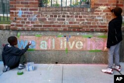 Two boys help finish a chalk mural at Marshall Field Garden Apartments during the Art on Sedgwick annual art show in Chicago, June 1, 2018.