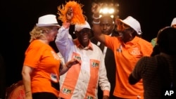 Ivory Coast incumbent President Alassane Ouattara, center, dances with his wife Dominique Ouattara, left, during his election rally in Abidjan, Ivory Coast, Oct. 23, 2015.
