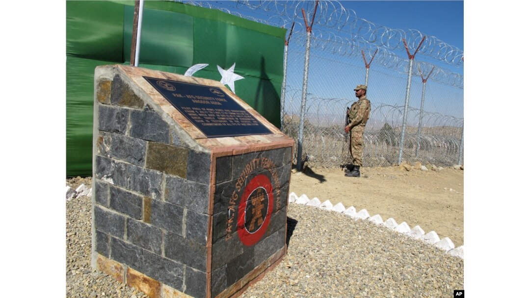 FILE - A Pakistani soldier stands guard at newly erected fence between Pakistan and Afghanistan at Angore Adda, Pakistan.
