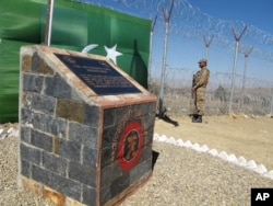 FILE - A Pakistani soldier stands guard at newly erected fence between Pakistan and Afghanistan at Angore Adda, Pakistan.