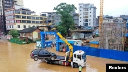 中國廣西柳州市的交通警察把街道上泡在洪水裡的汽車運走。 （2021年7月2日）