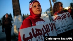 Một phụ nữ cầm tấm bảng với nội dung 'Nói không với chủ nghĩa khủng bố'