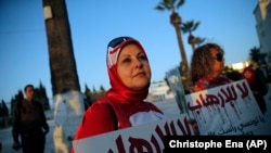 A woman holds a placard reading: "No to Terrorism" as she demonstrates in front of the National Bardo Museum a day after gunmen attacked the museum and killed scores of people in Tunis, Tunisia, Thursday, March 19, 2015.
