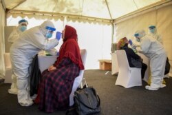 Para petugas kesehatan sedang melakukan tes usap (swab test) Covid-19 terhadap 28 orang yang tinggal di dalam kompleks Sekolah Calon Perwira Angkatan Darat (Secapa AD), di Bandung, Sabtu, 11 Juli 2020. (Foto: AFP)