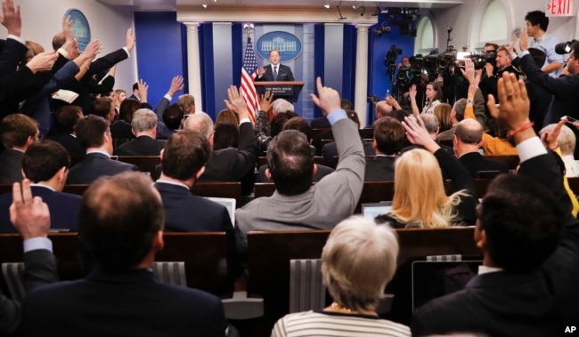 FILE - Reporters raise their hands as then-White House press secretary Sean Spicer takes questions during the daily briefing in the Brady Press Briefing Room of the White House in Washington, Feb. 22, 2017.