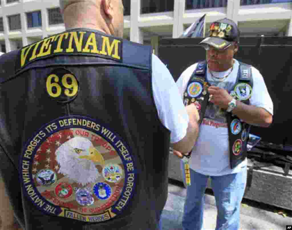 A Vietnam War veteran looks at the vest of Earl Christian, right, of The Bronx borough of New York, at New York City's Vietnam Veterans Memorial Plaza on Memorial Day, Monday, May 28, 2012. (AP Photo/Richard Drew)