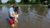 Gabby Aviles carries her daughter Audrey through floodwaters outside their apartment in Houston, Texas, May 26, 2015. 