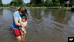 Gabby Aviles carries her daughter Audrey through floodwaters outside their apartment in Houston, Texas, May 26, 2015. 