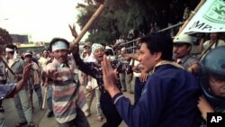 Massa pendukung pemerintah mengayunkan tongkat bambu, menyerang pengendara sepeda motor yang tidak bersalah di depan gedung DPRD di Jakarta, Selasa 10 November 1998. (Foto: dok).