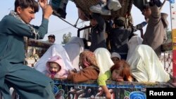 Families sit at the back of a van with their belongings, while fleeing a military offensive against the Pakistani Taliban, as they enter Bannu, located in Khyber Pakhtunkhwa province, Jan. 22, 2014. 