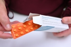 A pharmacist holds a box of dexamethasone tablets at a chemists shop in London on June 16, 2020. - The steroid dexamethasone was shown to be the first drug to significantly reduce the risk of death among severe COVID-19 cases in a trial.