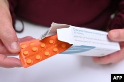 A pharmacist holds a box of dexamethasone tablets at a chemists shop in London on June 16, 2020. - The steroid dexamethasone was shown to be the first drug to significantly reduce the risk of death among severe COVID-19 cases in a trial.