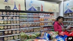 FILE - In this photo taken March 17, 2017, a vendor takes stock of imported food at a mall in Beijing, China. 