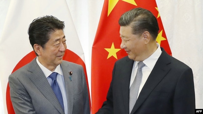 日本首相安倍晋三和中国国家主席习近平（右）在俄罗斯举行的东方经济论坛上握手。（2018年9月12日）