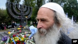 FILE - People lay flowers at a menorah monument close to the Babi Yar ravine where the Nazis machine-gunned tens of thousands of Jews during WWII, in Kyiv, Ukraine, Sept. 30, 2012.