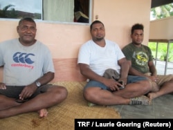 Rupeni Koto, who fled his home in Nasau, a village on Fiji's Koro island, after 2016's Cyclone Winston, sits on a porch with two of his sons, Soan, 25 (center) and Sekove, 21 (right), in the Fijian capital, Suva, Feb. 8, 2018.
