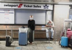 Passengers wait for confirmation of flights outside the Swissport Ticket Sales counter as several airlines stopped flying out of South Africa, amidst the spread of the new Omicron variant at O.R. Tambo International Airport in Johannesburg, South Africa,