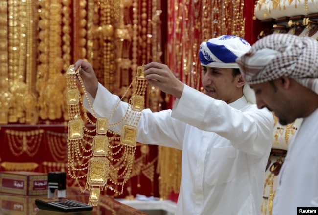 An employee shows a customer gold jewellery in a shop at the Gold Souq in Dubai, United Arab Emirates, March 24, 2018.
