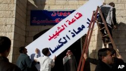 Warga desa Ai di Karak, Yordania memasang nama "gedung martir pilot Muath al-Kaseasbeh," di tempat kelahiran pilot Yordania yang tewas dibunuh ISIS (4/2).