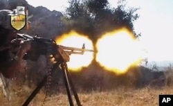 FILE - In this file image taken from video obtained from the Shaam News Network, a jihadi-led rebel fighter fires a gun in a valley in Latakia province, Syria. Rebels killed at least 190 civilians and abducted more than 200 during an offensive against pro-regime villages, committing a war crime, an international human rights group said, Oct. 11, 2013.