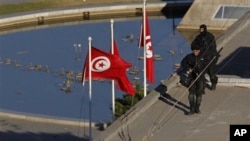 Soldiers stand guard atop a building the center of Tunis, 15 Jan 2011