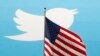FILE - The Twitter Inc. logo is shown with the U.S. flag during the company's IPO on the floor of the New York Stock Exchange in New York, Nov. 7, 2013. 