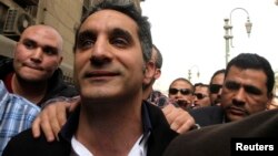 Bassem Youssef (C), the country's best-known satirist, gestures to journalists and activists as he arrives at the high court to appear at the prosecutor's office in Cairo Mar. 31, 2013.