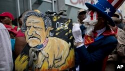 A protester mocking Uncle Sam holds a painting of OAS leader Luis Almagro at a rally against the United States and possible OAS sanctions, in Caracas, Venezuela, March 28, 2017, as OAS diplomats meet in Washington.