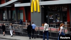 People walk past a closed McDonald's restaurant, one of four temporarily closed by the state food safety watchdog in Moscow, August 21, 2014