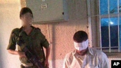 A handout picture from Israeli human rights organization Breaking the Silence, 18 Aug 2010, shows an undated photograph of an Israeli soldier posing near a handcuffed and blindfolded Palestinian detainee at an undisclosed location
