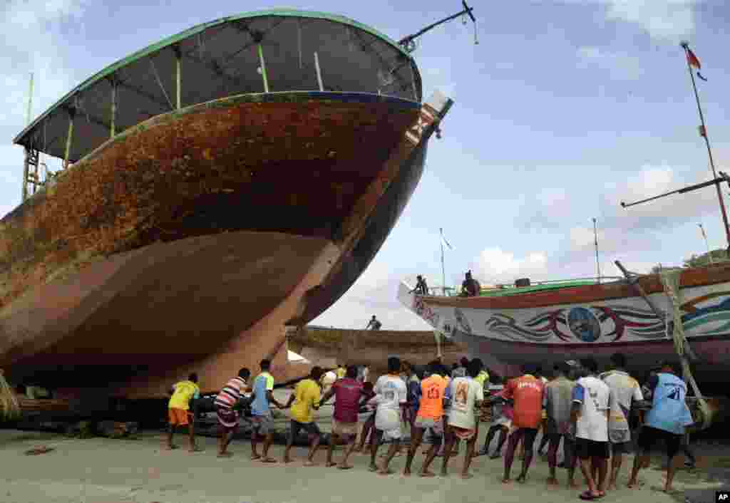 Fishermen pull a boat ashore on the Arabian sea coast ahead of monsoon rains at Thane district near Mumbai, India.