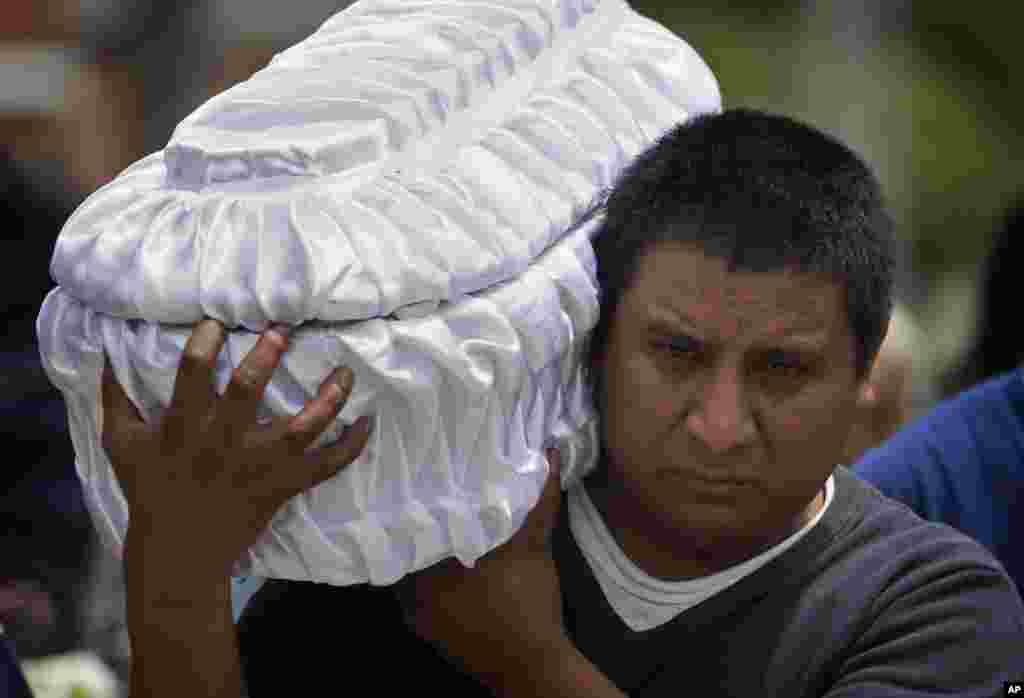 Welsar Nazario carries the coffin of his five-month-old nephew Alezandro Macario, who died in a mudslide, to the Santa Catarina Pinula cemetery on the outskirts of Guatemala City, Oct. 3, 2015. Rescue workers recovered more bodies after a hillside collapsed on homes on Oct. 1, while more are feared still buried in the rubble.