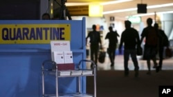 FILE - Passengers walk past the medical quarantine area showing information sheets for the Middle East respiratory syndrome coronavirus at the arrival section of Manila's International Airport in Paranaque, south of Manila, April 16, 2014..