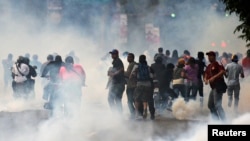 Supporters of opposition leader Henrique Capriles run from tear gas fired by riot police as they rally for an election recount, Caracas, April 15, 2013.